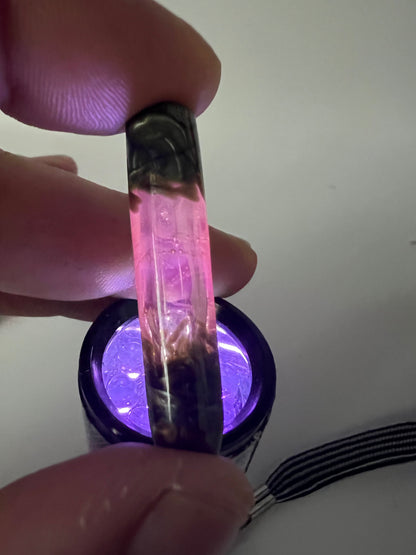 Boquilla de vidrio UV rosa y Electrum reaccionando bajo luz ultravioleta con brillo rosa fluorescente.